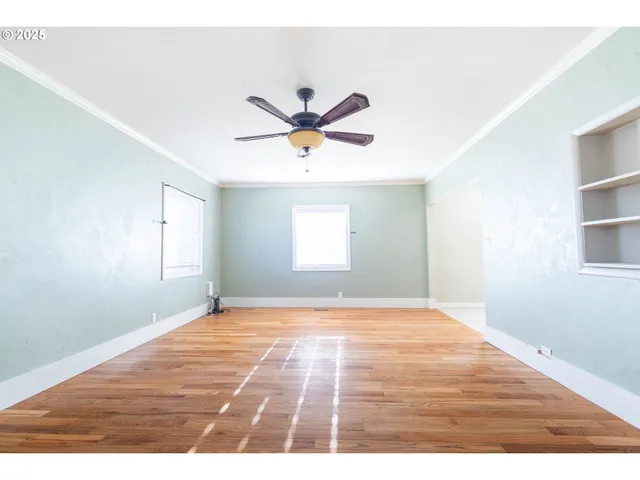 a view of an empty room with window and a kitchen