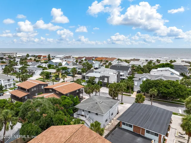 an aerial view of residential houses with outdoor space and a lake view