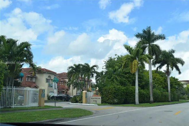 a view of a white house with a big yard and palm trees