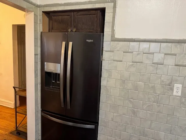 a view of a refrigerator in kitchen and an empty room in wooden floor