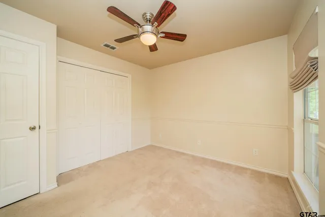 an empty room with a ceiling fan and a window