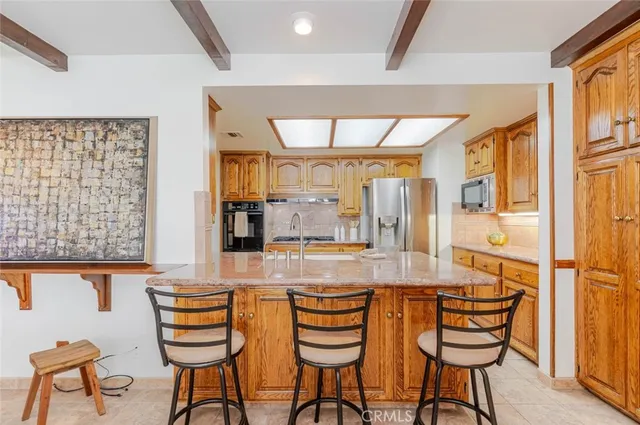 a kitchen with stainless steel appliances granite countertop a refrigerator a sink and white cabinets