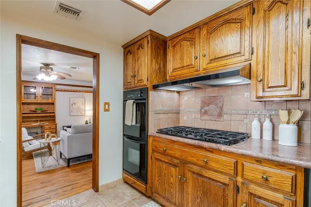 a kitchen with stainless steel appliances granite countertop a refrigerator a stove and wooden cabinets with wooden floor