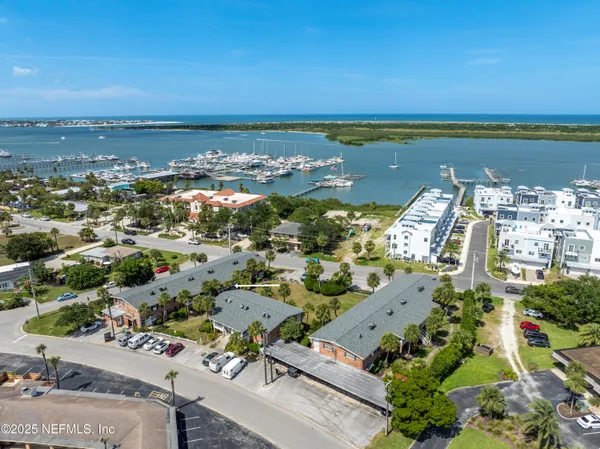an aerial view of ocean and residential houses with outdoor space