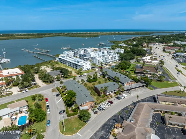 an aerial view of ocean and residential houses with outdoor space