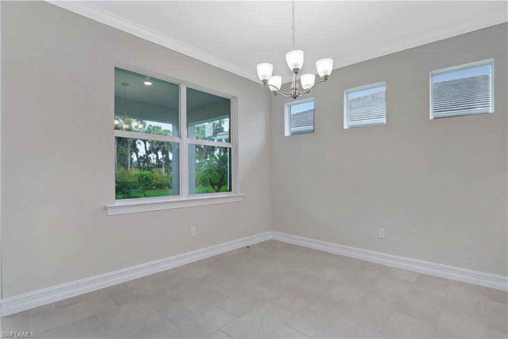 335 Tamarindo Lane Naples, FL 34114 - Photo 10 of 38 en empty room with windows and chandelier