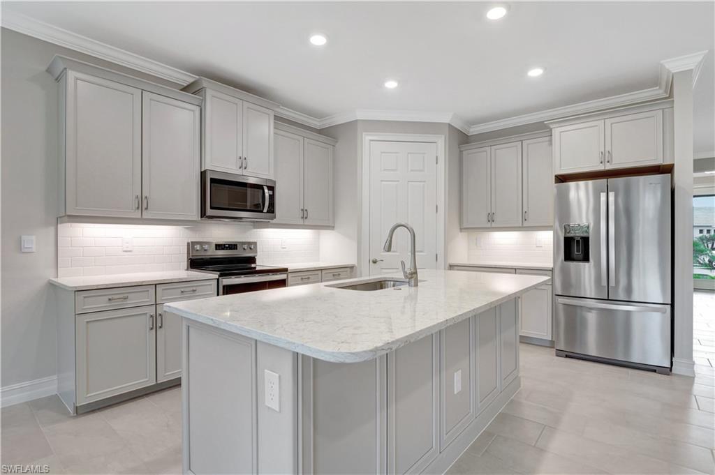 335 Tamarindo Lane Naples, FL 34114 - Photo 2 of 38 Kitchen featuring stainless steel appliances, ornamental molding, backsplash, light stone counters, and recessed lighting