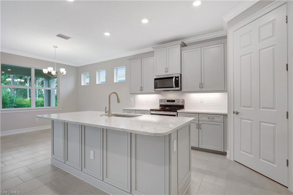 335 Tamarindo Lane Naples, FL 34114 - Photo 5 of 38 a kitchen with appliances a sink and cabinets