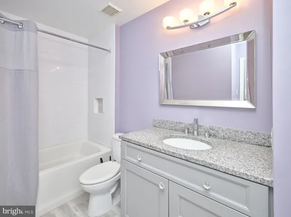 a bathroom with a granite countertop sink toilet mirror and bathtub