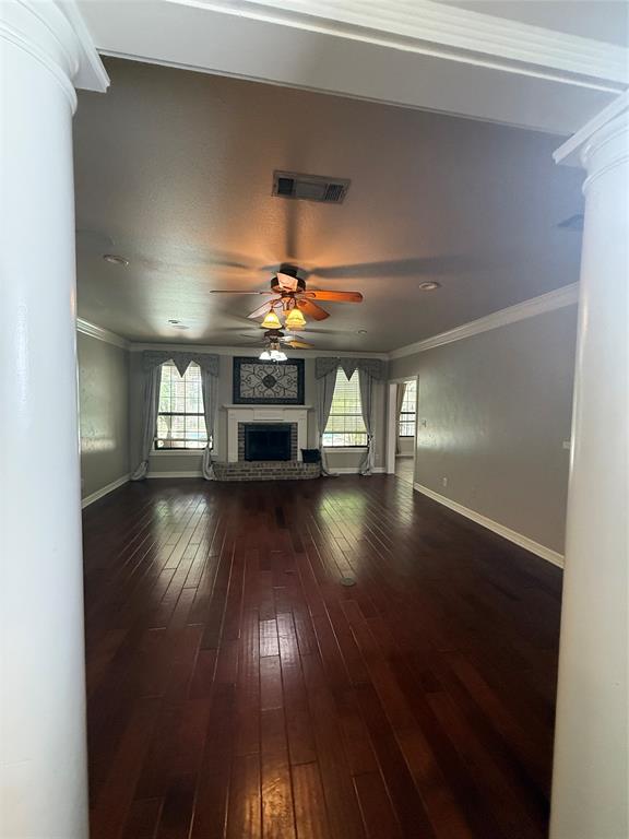 201 Woodhaven Drive Minden, LA 71055 - Photo 6 of 31 Spacious interior featuring dark wood-finish flooring, a traditional brick fireplace with a white mantel, and ceiling fan with integrated lighting