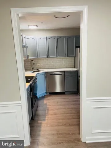 a large white kitchen with a sink and dishwasher a stove with wooden floor