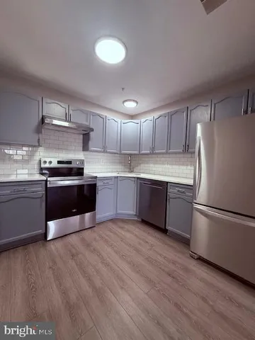 a kitchen with stainless steel appliances a stove a sink and white cabinets