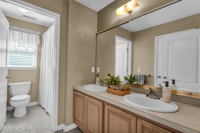 a bathroom with a double vanity sink toilet and a mirror