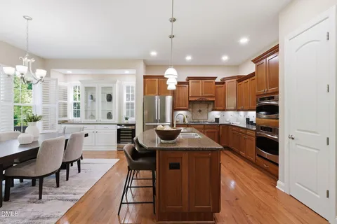 a white kitchen with granite countertop a potted plant on a sink and a potted plant