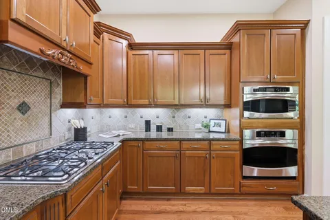 a kitchen with stainless steel appliances a table chairs refrigerator and microwave
