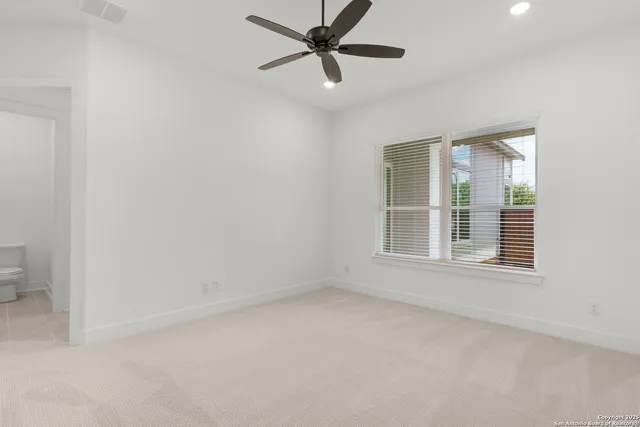 an empty room with a window and a fan