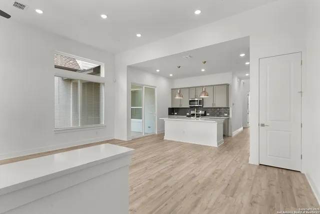 a view of kitchen with kitchen island granite countertop wooden floor and stainless steel appliances