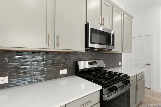a kitchen with granite countertop a sink a stove and cabinets