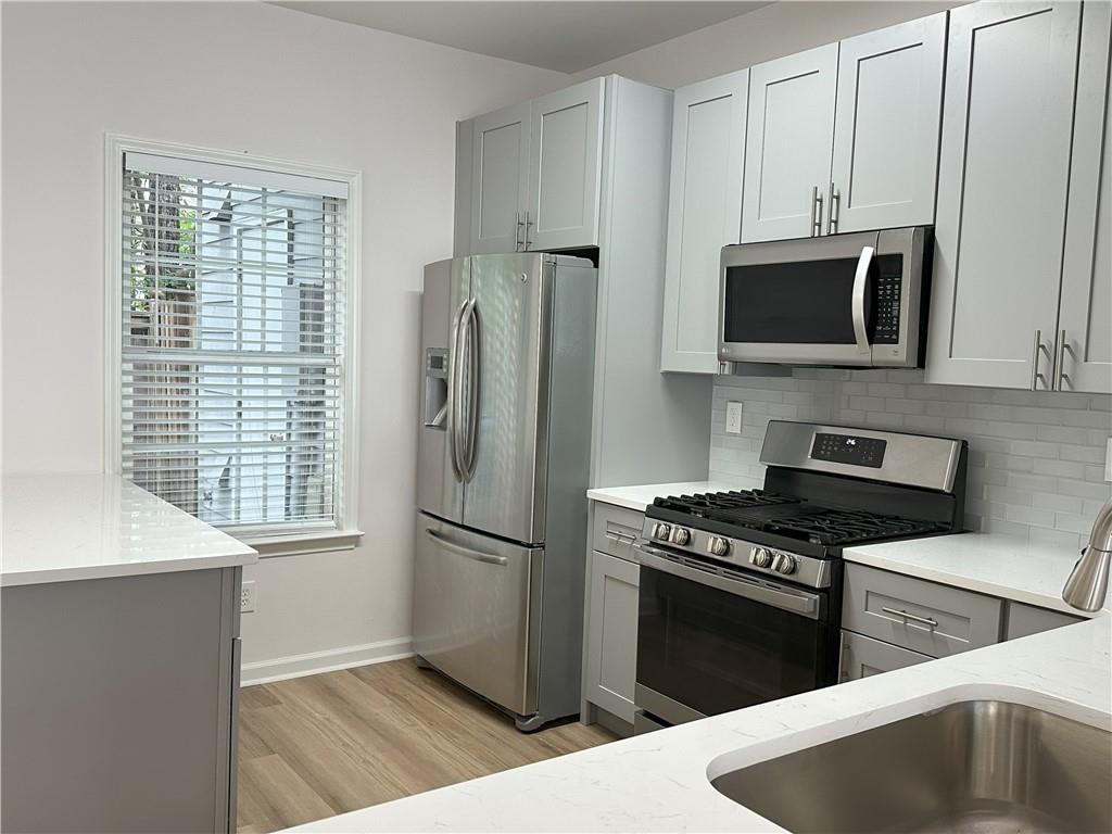 4162 Howell Park Road Duluth, GA 30096 - Photo 5 of 16 a kitchen with granite countertop a refrigerator a stove a microwave and cabinets