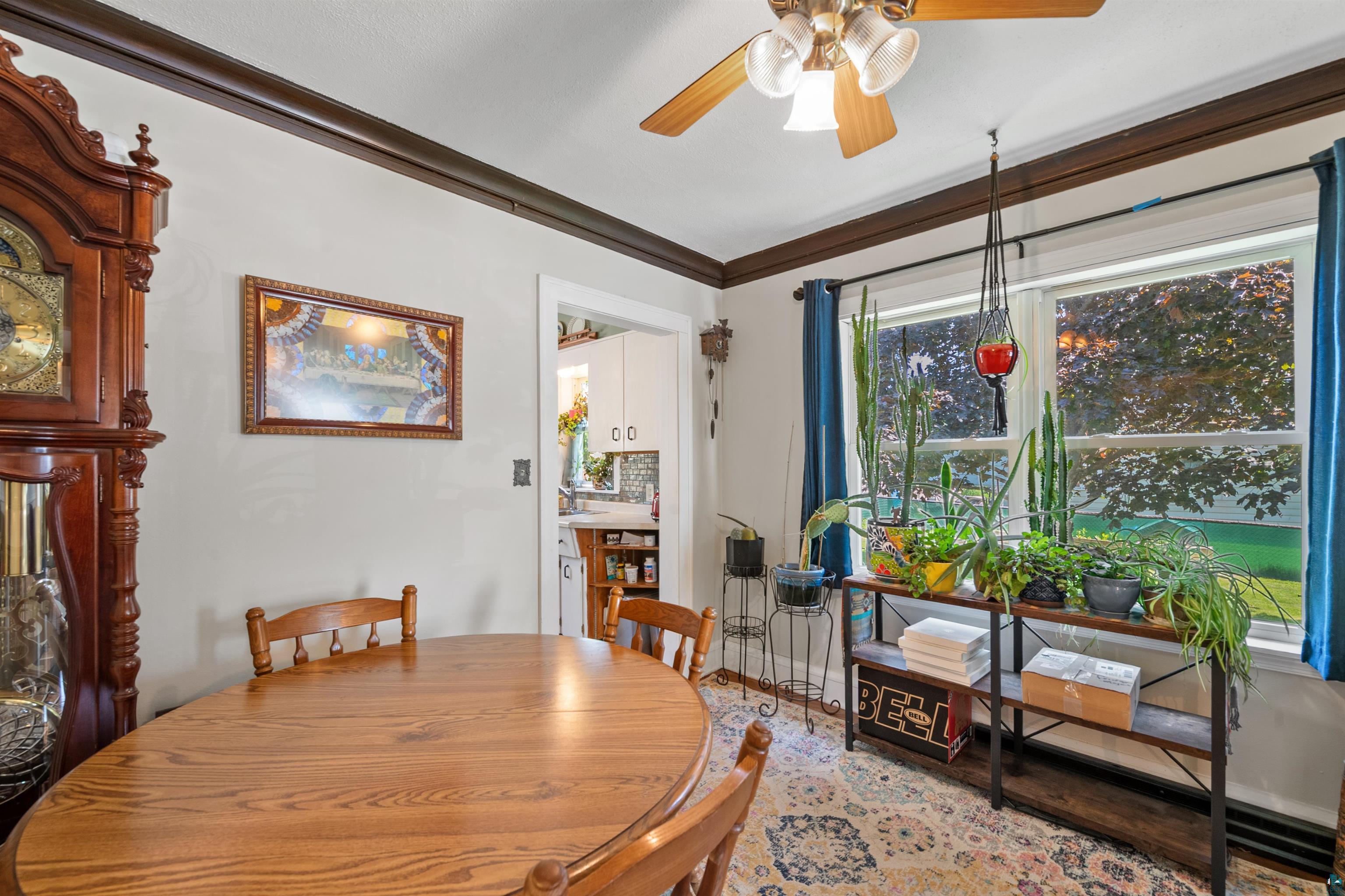3209 Chestnut Street Duluth, MN 55806 - Photo 9 of 28 Dining area featuring a ceiling fan with integrated lighting, dual windows with blue drapery, and a doorway opening to the kitchen