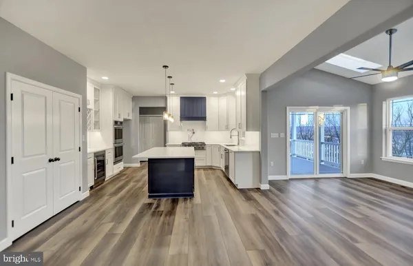 a living room with stainless steel appliances kitchen island granite countertop furniture wooden floor and view living room