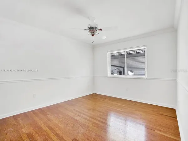 an empty room with a chandelier fan and windows