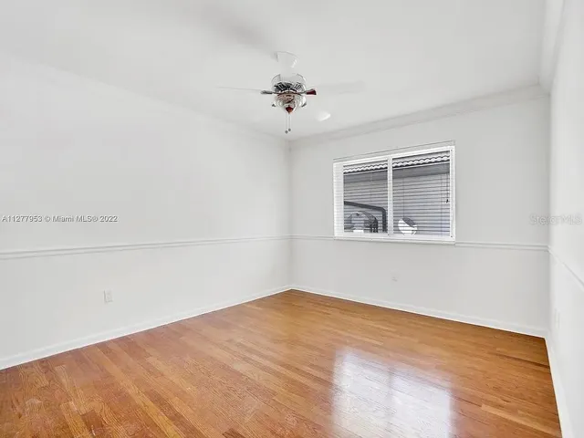 an empty room with a chandelier fan and windows
