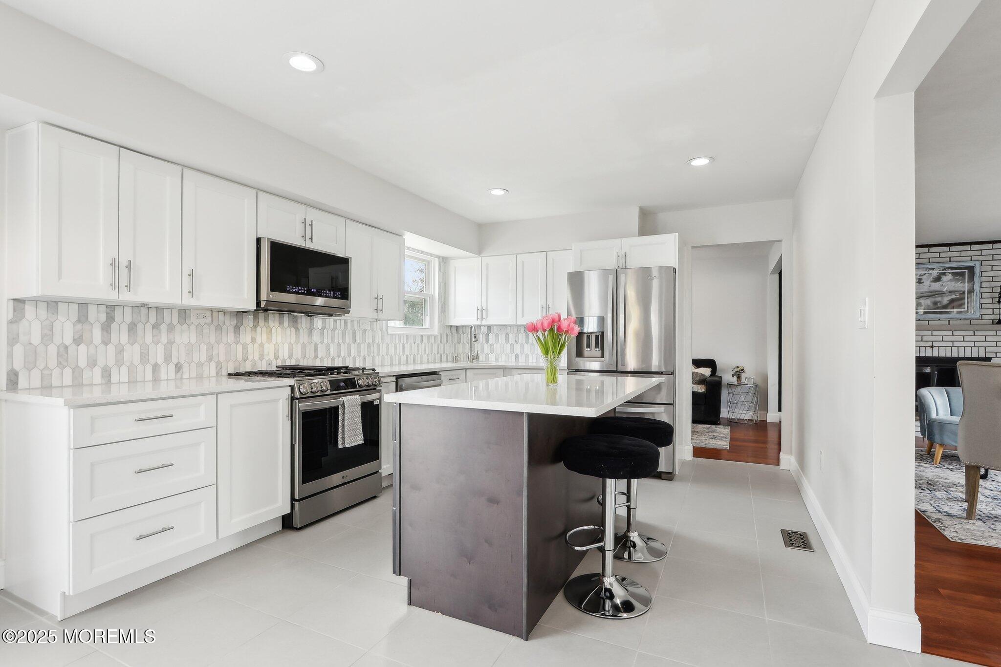572 Line Road Hazlet, NJ 07730 - Photo 21 of 39 a kitchen with stainless steel appliances kitchen island granite countertop a stove top oven a sink dishwasher a dining table and chairs with wooden floor