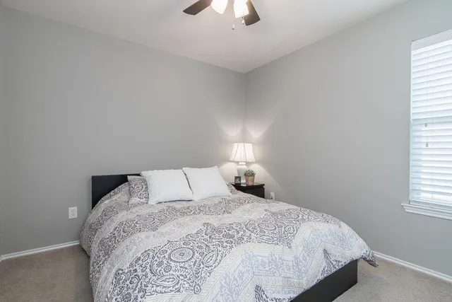 a bedroom with a bed and a chandelier fan