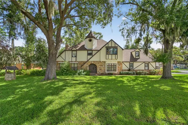 a view of a house with a big yard and large trees