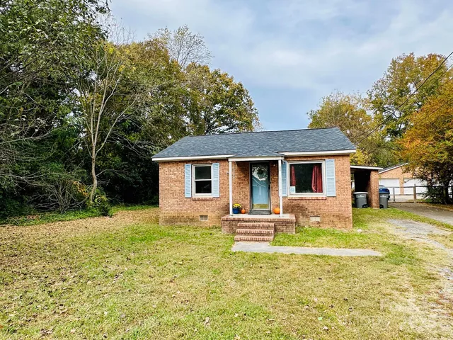 a front view of house with yard and trees in the background
