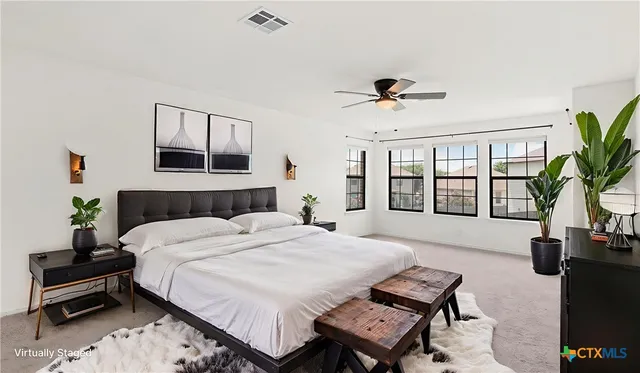 a bedroom with a bed a couch and a potted plant on the dresser