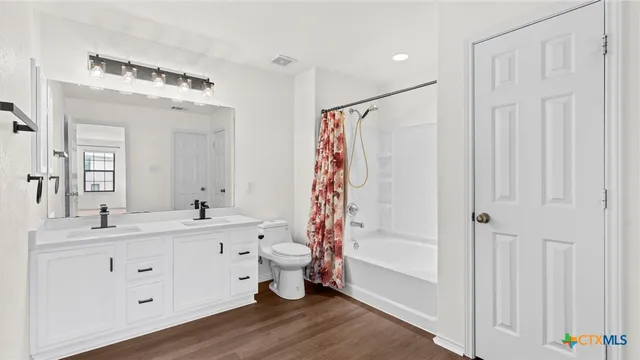 a bathroom with a double vanity sink a mirror a vanity and a bathtub