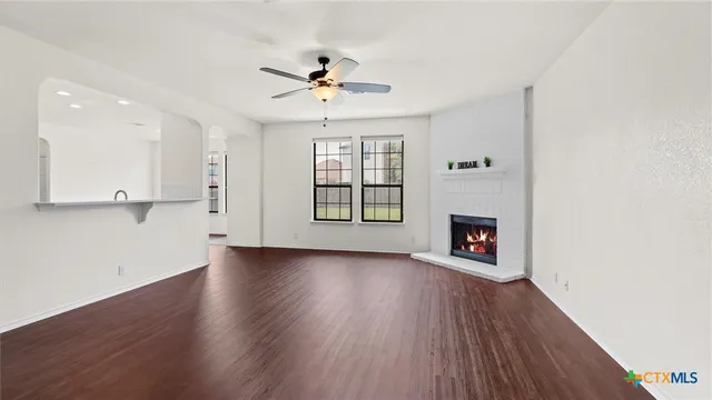a view of an empty room with a fireplace and wooden floor