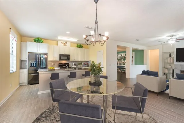 a kitchen with refrigerator a kitchen island dining table and chairs