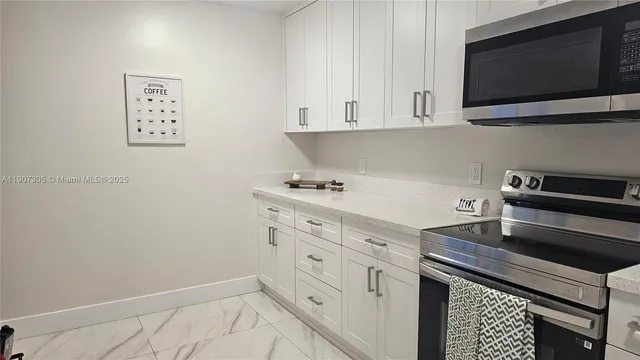 a kitchen with stainless steel appliances white cabinets and a stove top oven