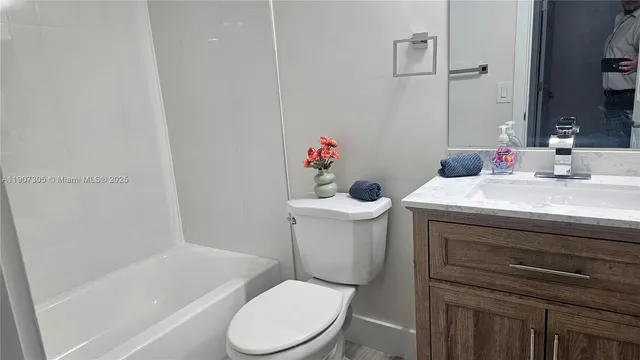a white toilet sitting next to a bathroom sink and vanity