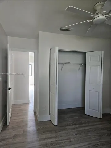 an empty room with wooden floor & closet area
