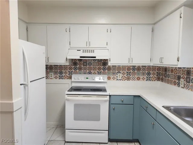 a white refrigerator freezer and a stove sitting inside of white cabinets