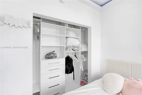 a bedroom with bed and a flat tv screen on dresser