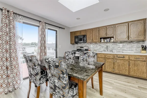 a kitchen with kitchen island granite countertop a table chairs sink and cabinets