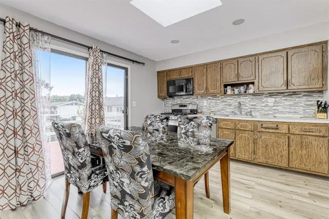 a kitchen with kitchen island granite countertop a table chairs sink and cabinets