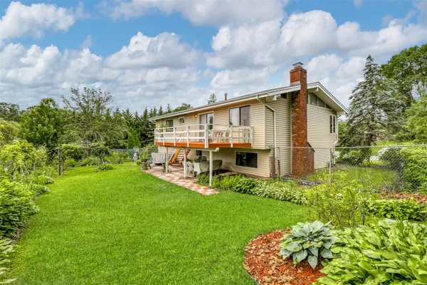 a view of a house with a big yard plants and large trees