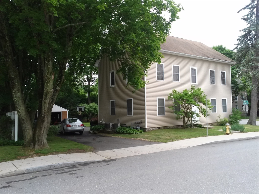 a front view of a house with a garden and trees