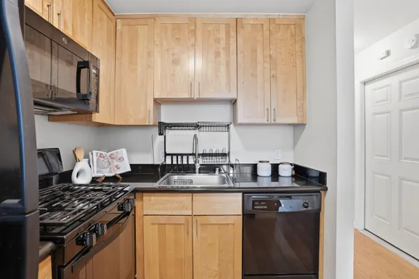 a kitchen with stainless steel appliances granite countertop a stove a sink dishwasher and cabinets with wooden floor
