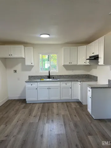 a kitchen with granite countertop a sink cabinets and wooden floor