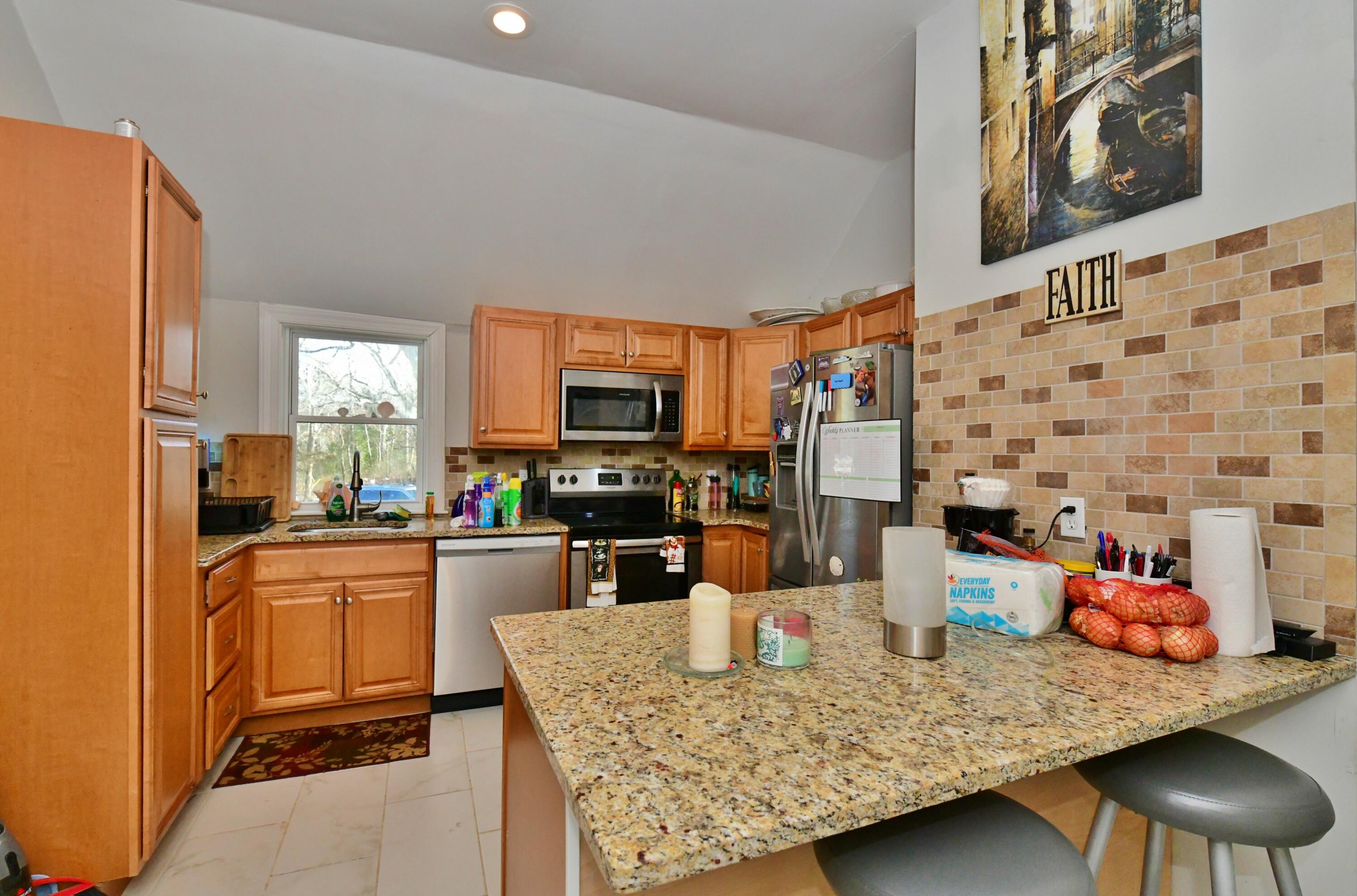 26 Old Monument Neck Road Bourne, MA 02532 - Photo 17 of 51 a kitchen with stainless steel appliances granite countertop a sink dishwasher stove a refrigerator a dining table and chairs with wooden floor