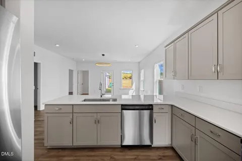a kitchen with a sink dishwasher and cabinets with wooden floor
