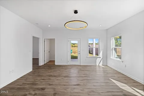a view of an empty room with wooden floor and window