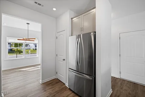 a view of a refrigerator in kitchen and an empty room